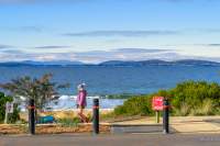 Woman walking a dog at Blackmans Bay beach